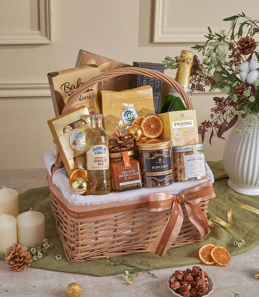Golden wicker gourmet basket with champagne, chocolates, coffee, tea, and artisan treats for New Year celebrations
