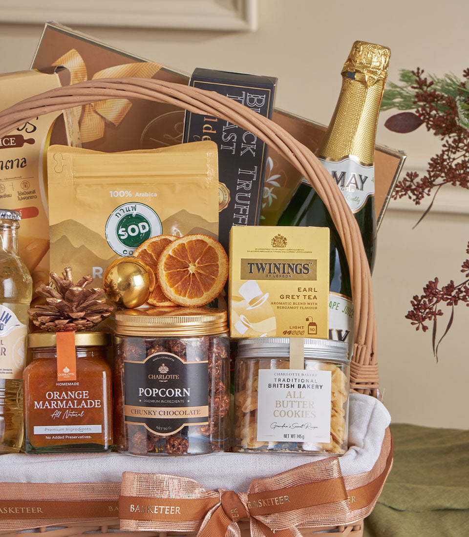 Basketeer premium hamper with gourmet goodies: champagne, chocolate popcorn, marmalade & Earl Grey tea in a wicker basket with bronze ribbon. Perfect corporate gift.