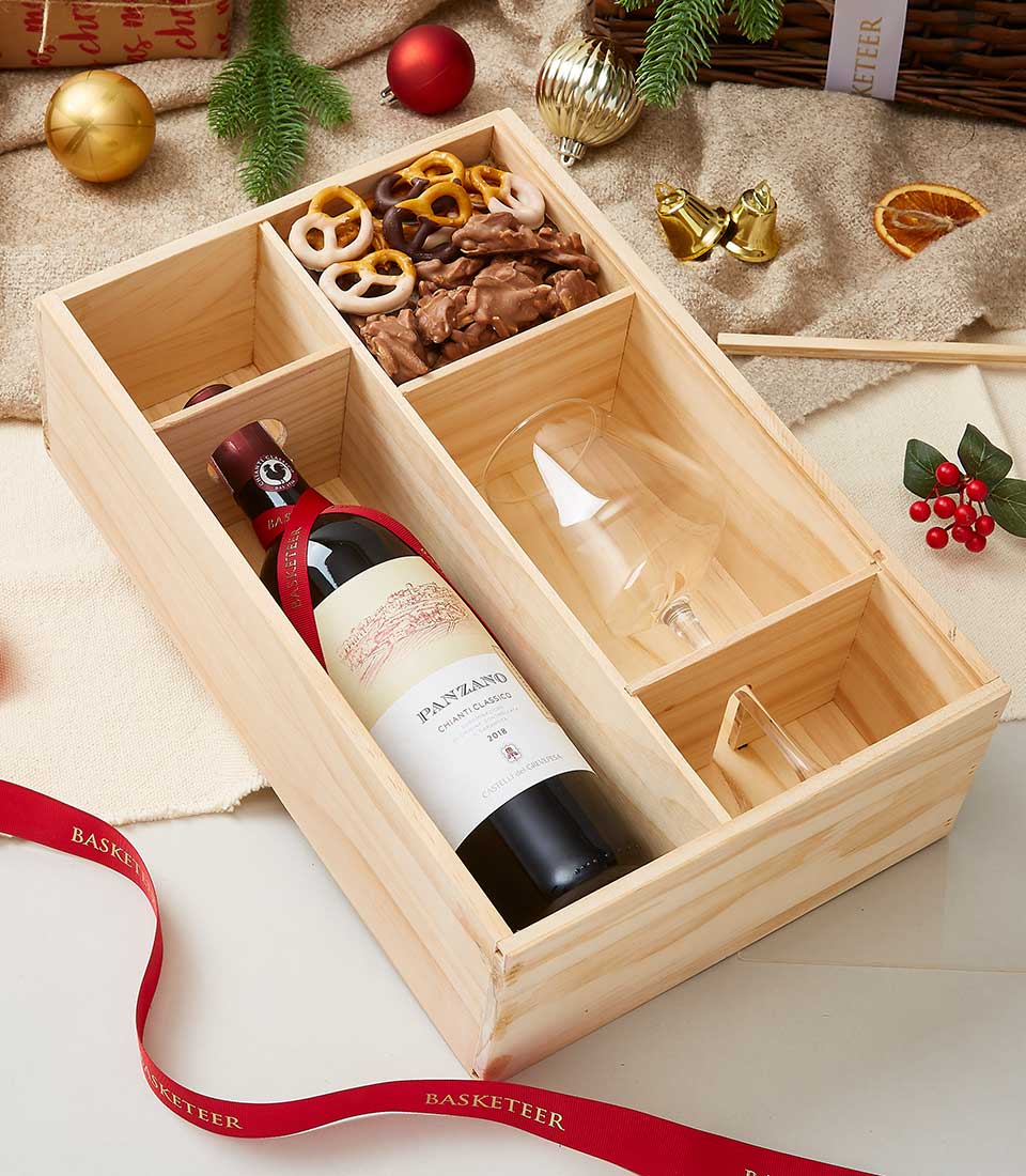 Premium wooden wine gift box with red wine, wine glass, and chocolate treats, festive holiday presentation