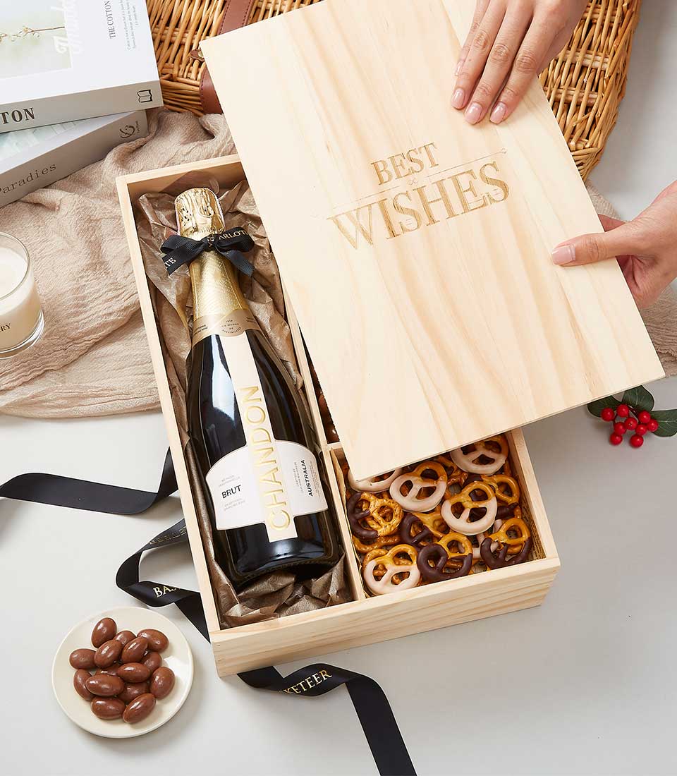 Wooden gift box with Chandon sparkling wine, chocolate pretzels, and festive red berries for celebrations