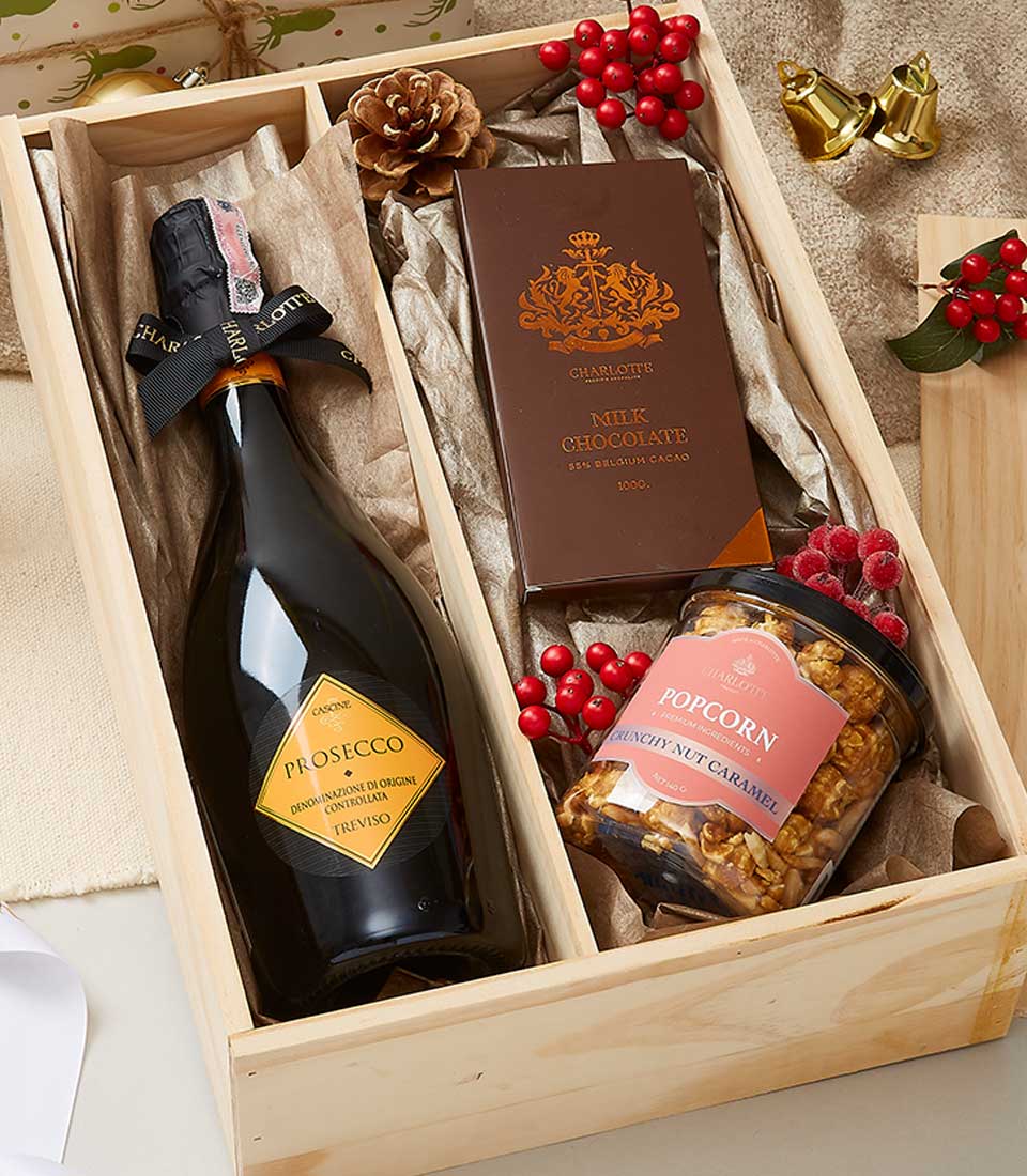 Prosecco, artisan chocolate, and caramel popcorn in wooden gift box with festive trimmings