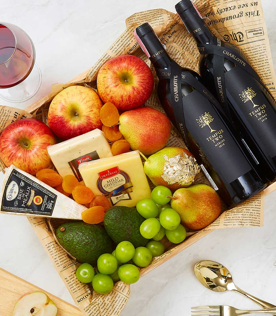 Luxury wooden crate gift hamper with two red wine bottles, artisan cheeses, fresh fruit, and gold-leaf pear