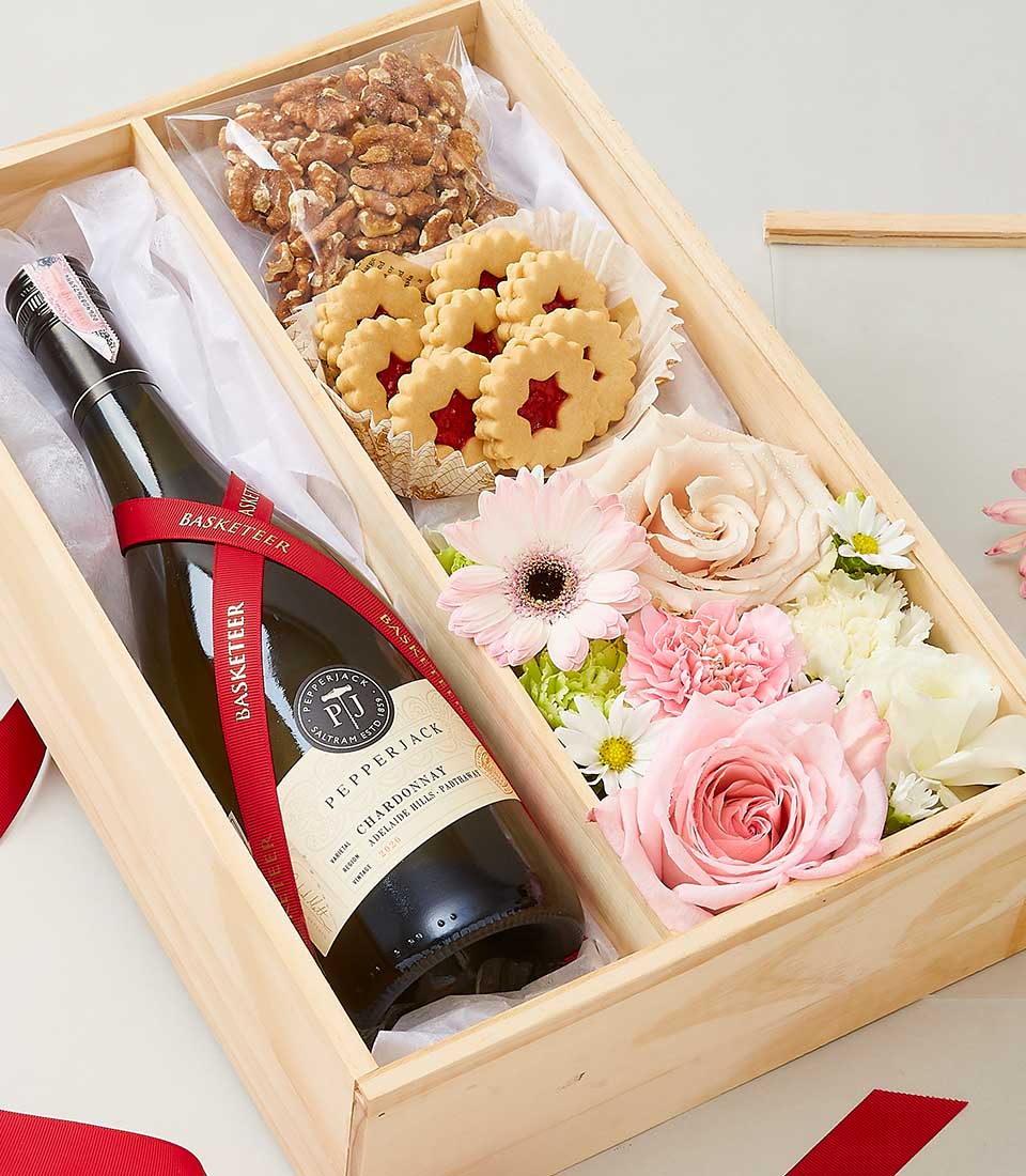 Elegant wooden gift box with white wine, walnut cookies, fresh pink roses and gerberas