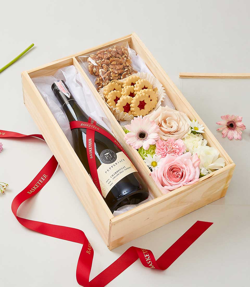 Elegant wooden gift box with white wine, star cookies, walnuts, and fresh pink and white roses