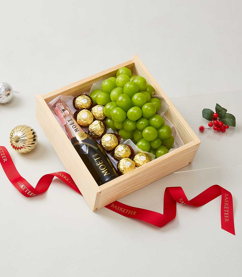 Deluxe wine and grapes gift box with champagne, chocolates, and fresh green grapes in wooden crate