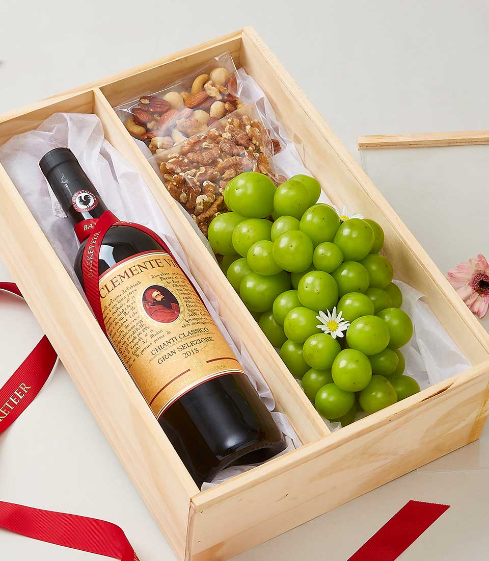 Chianti wine, mixed nuts, and fresh grapes in wooden gift box with red ribbon