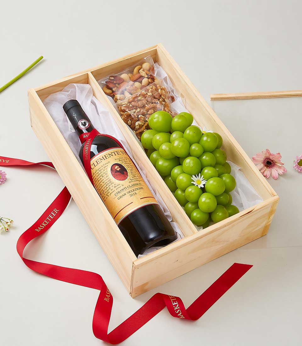 Chianti red wine with roasted nuts and fresh green grapes in a wooden gift box