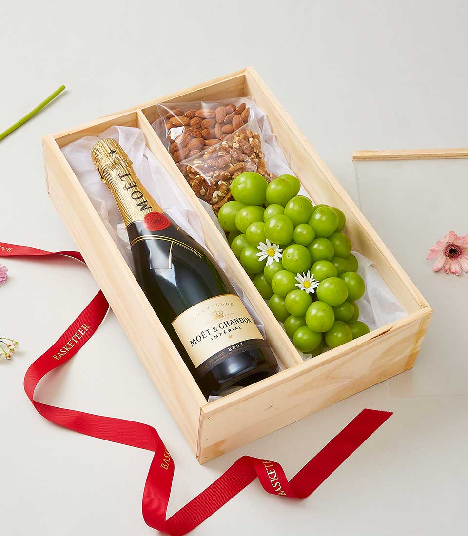Luxury wooden champagne gift box with Moët & Chandon bottle, roasted nuts, and fresh green grapes with flowers