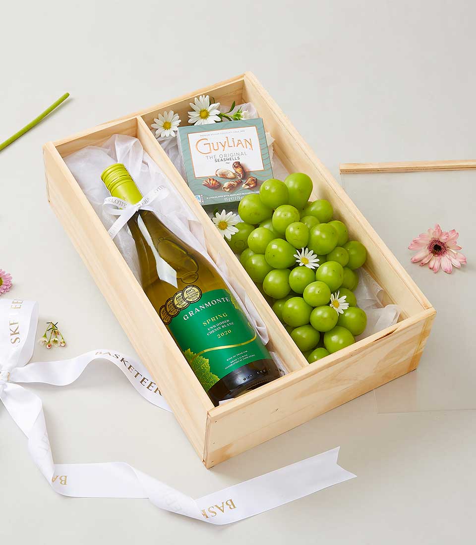 Premium white wine gift box with artisan chocolates and fresh grapes in wooden compartments
