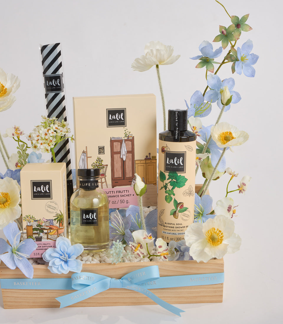 # Alt Text

Lalif home fragrance gift set in wooden basket with blue ribbon, featuring candles, room spray, and diffuser surrounded by fresh flowers.