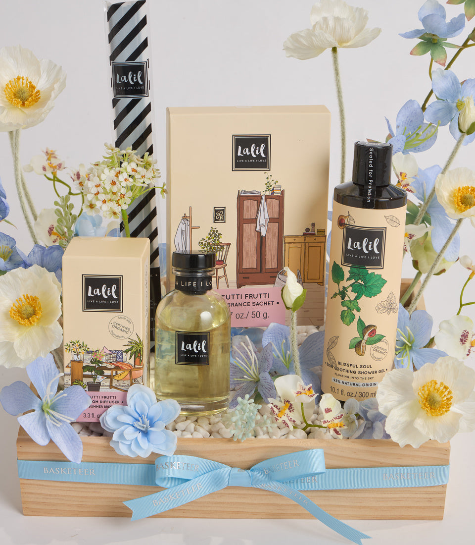 Lalif spa gift set in wooden basket with cream packaging, glass bottle, shower gel, sachets, blue flowers, and light blue ribbon bow.