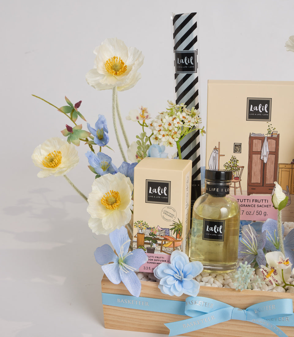Lafel home fragrance gift set with white peonies, blue flowers, striped packaging, cream boxes, glass perfume bottle, and wooden basket with blue ribbon.