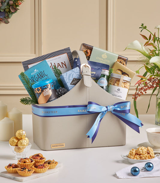 Grey faux leather gourmet tea and coffee gift basket with organic treats, festive blue ribbon, and curated luxury items for
