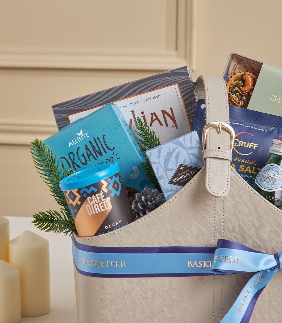 Elegant beige leather gourmet gift basket with organic tea, specialty coffee, chocolates, and premium snacks for New Year