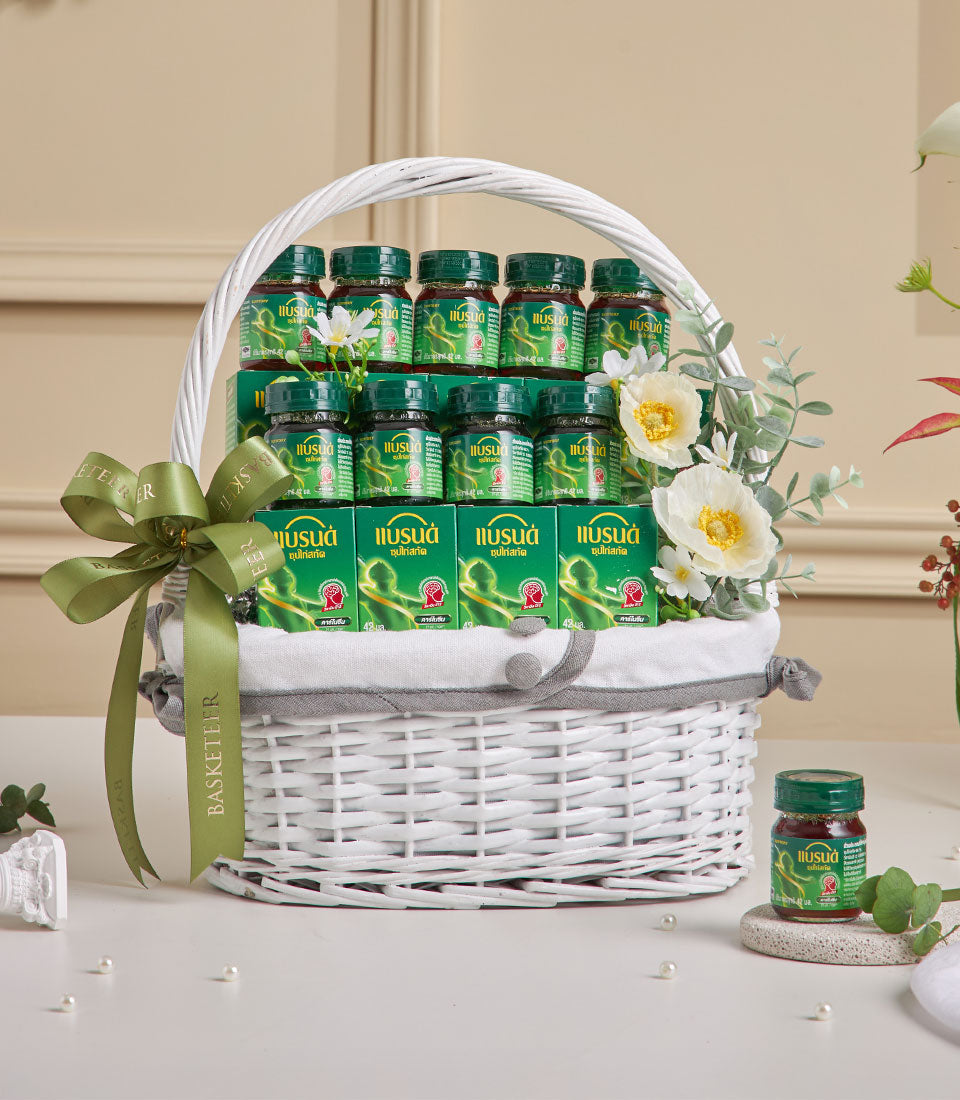 Luxury wellness gift basket with green herbal balm jars, satin ribbon, and fresh flowers