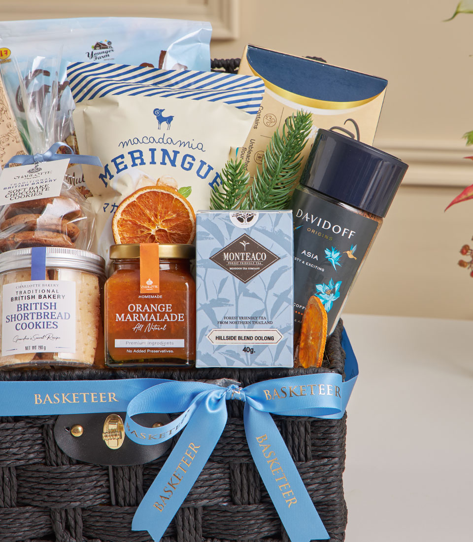 Luxury gift basket with blue ribbon featuring gourmet tea, coffee, shortbread, marmalade, and macadamia meringue for New