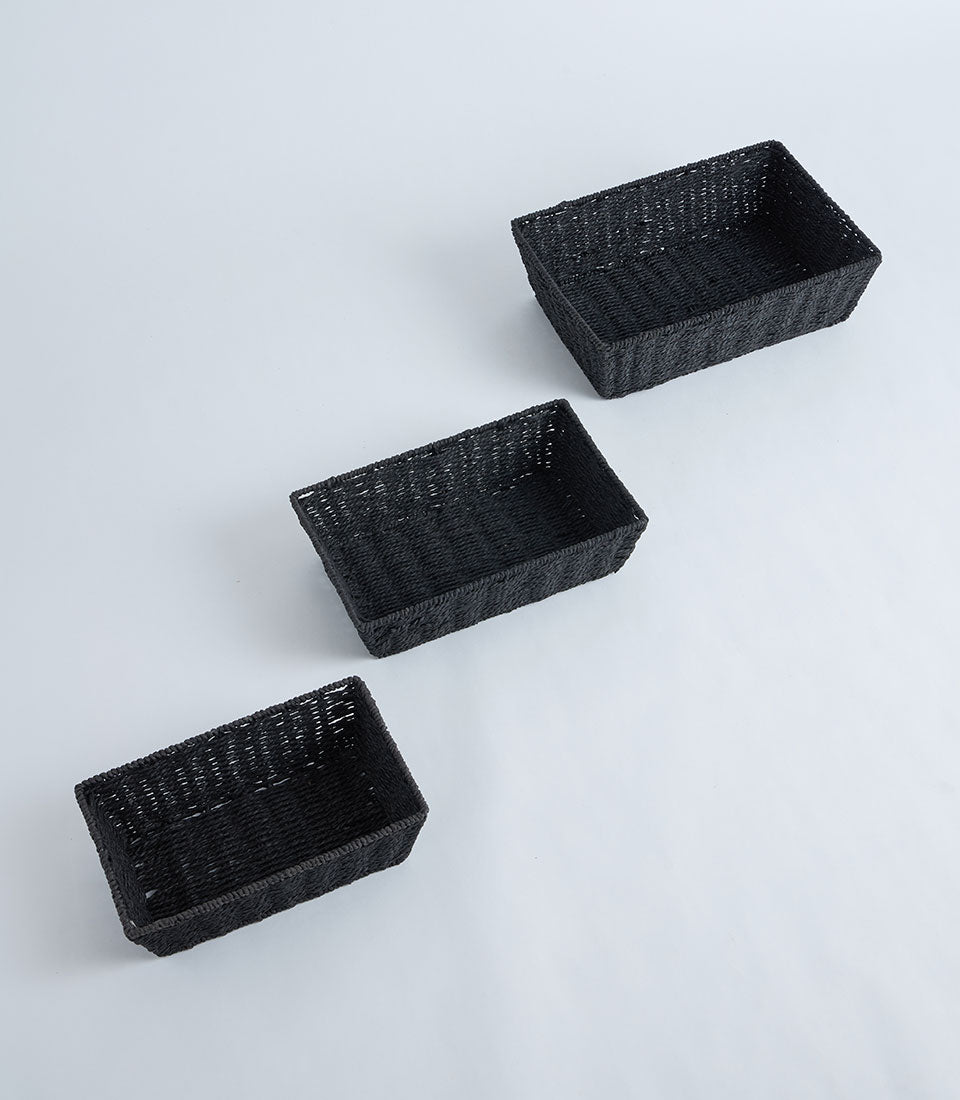 Dark woven rectangular baskets in black wicker, nested arrangement on white background