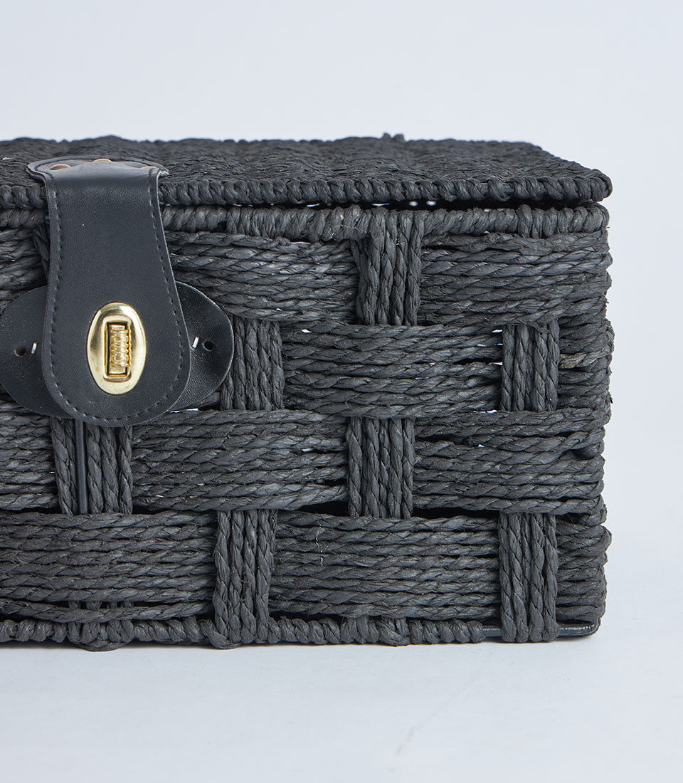 Black woven storage basket with leather lock and gold clasp, natural fiber construction