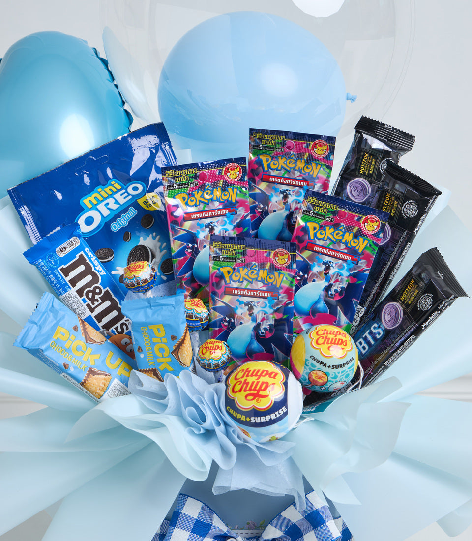 Blue balloon bouquet with Pokémon cards, Chupa Chups lollipops, M&M's, Oreo cookies, and BTS merchandise arranged with white tulle and checkered base.