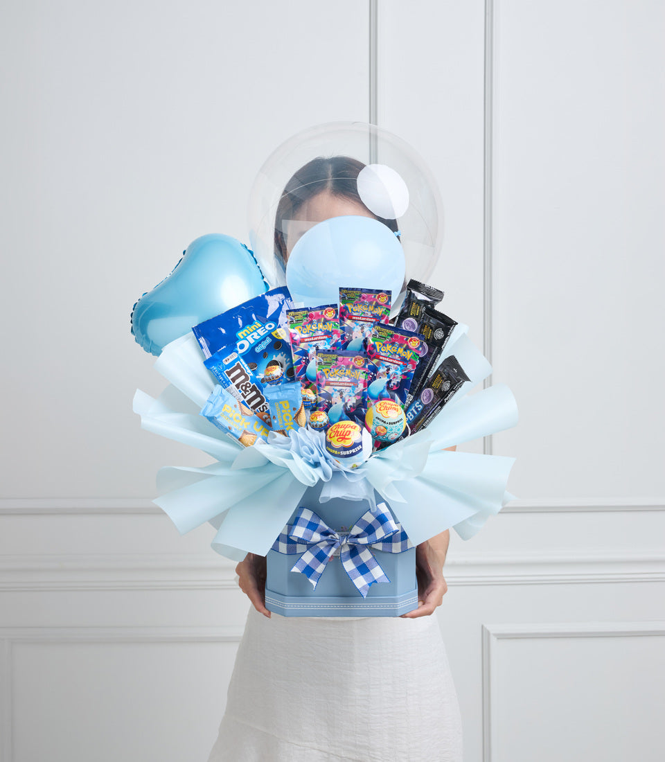 Blue and white candy bouquet with balloons, featuring colorful wrapped sweets, M&Ms, Oreos, and a checkered blue ribbon bow on a light background.