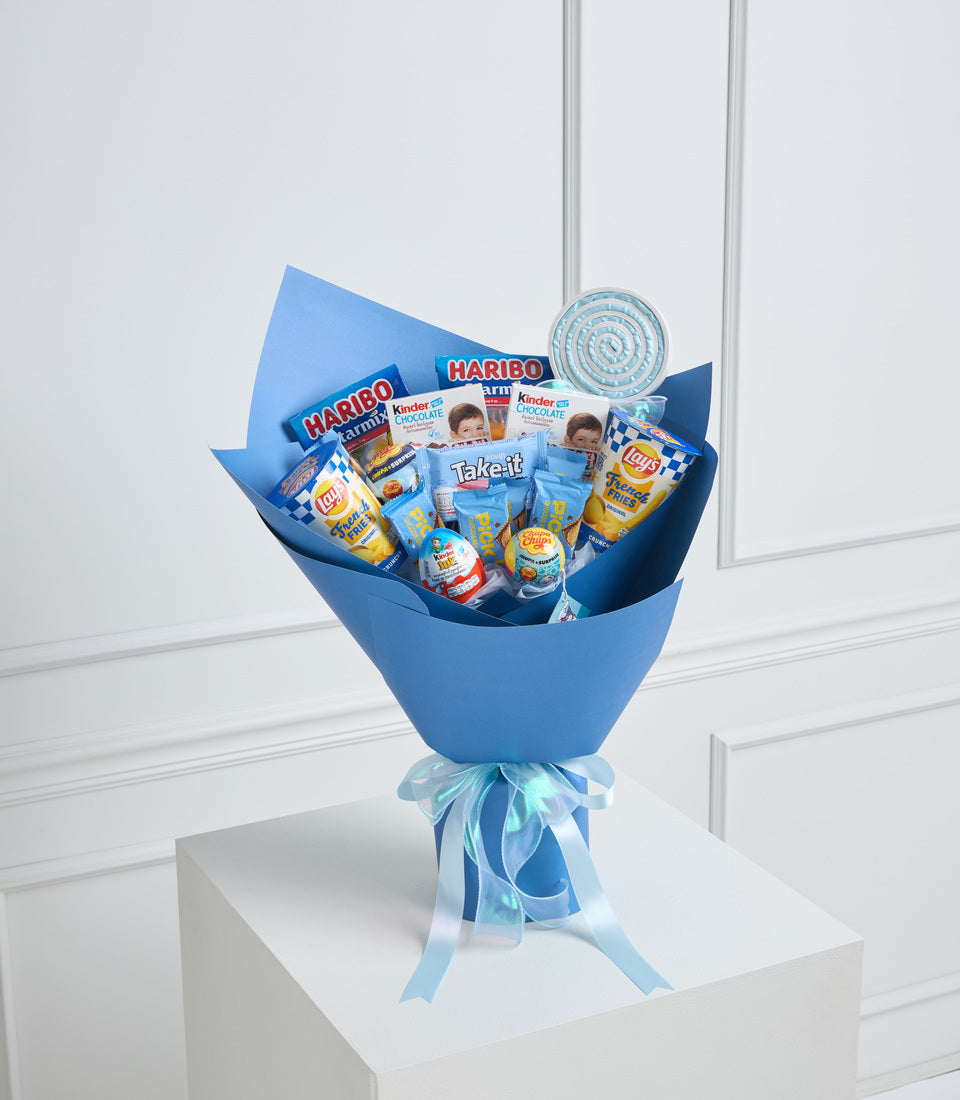 Blue gift bouquet filled with snacks and candies including Haribo, Kinder, Lay's, and Takeit, wrapped with blue ribbons on white pedestal.
