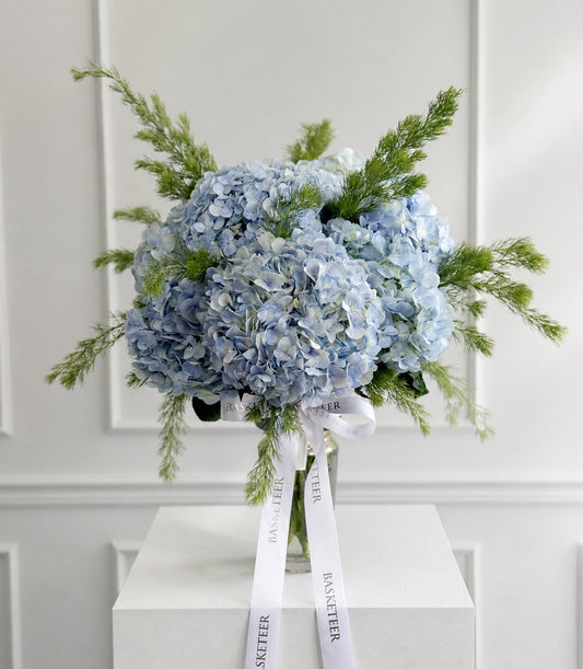 A lush arrangement of delicate pastel blue hydrangeas and fresh green foliage in a