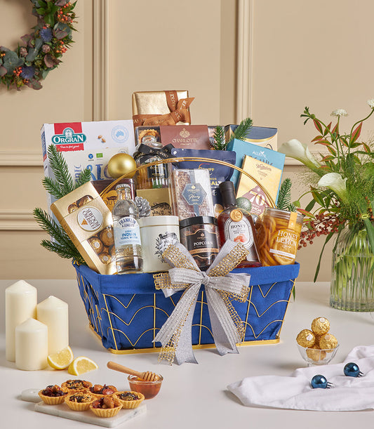 Royal blue luxury gourmet basket with Ferrero Rocher chocolate, honey, and popcorn, adorned with silver and gold ribbon for