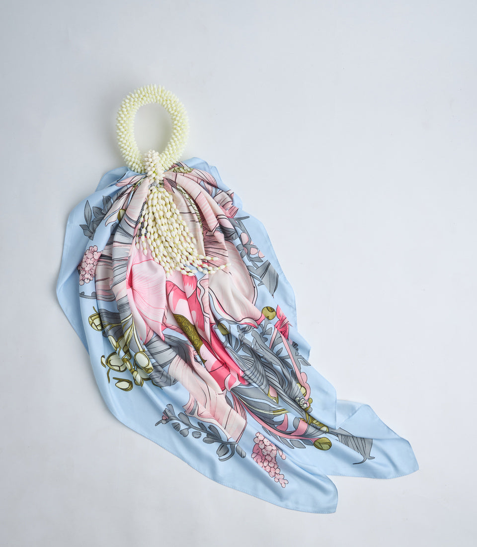 Light blue silk scarf with pink floral botanical print, tied with cream beaded handle, displayed against white background.