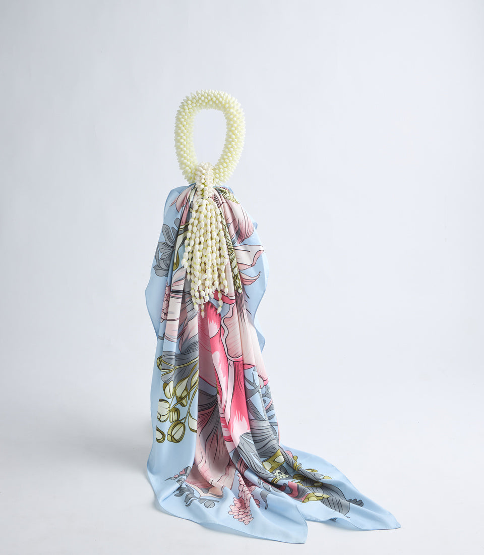Decorative silk scarf with anatomical floral design in blue, pink, and gold, styled with a cream pearl beaded necklace loop.