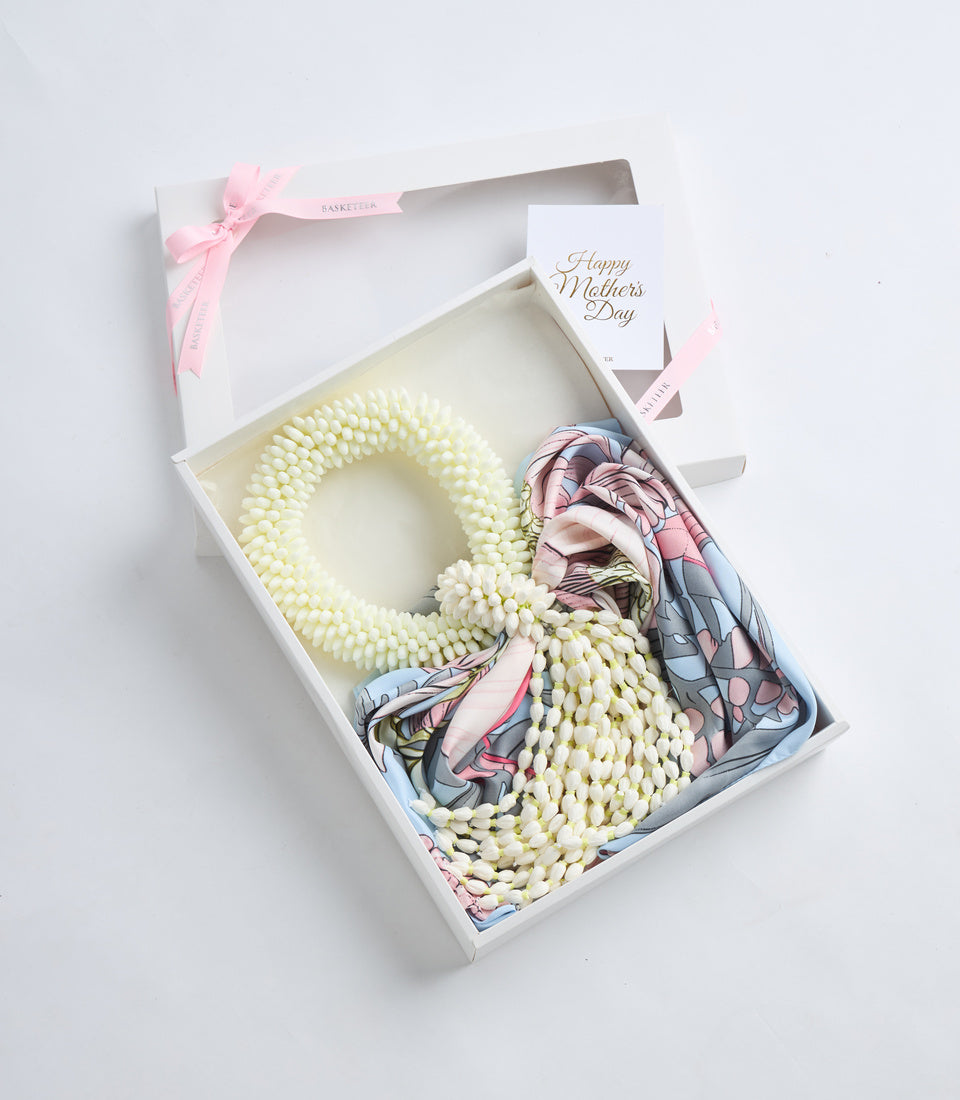 White gift box containing cream pearl beaded wreath, colorful patterned scarf, and Happy Mother's Day card with pink ribbon bow.
