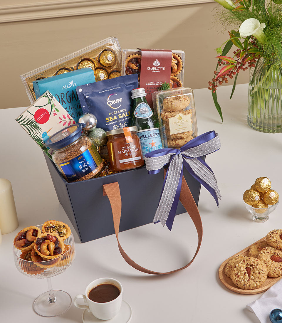 Premium chocolate and coffee gift hamper with gold foil treats, marmalade, and cookies in navy box with leather handles