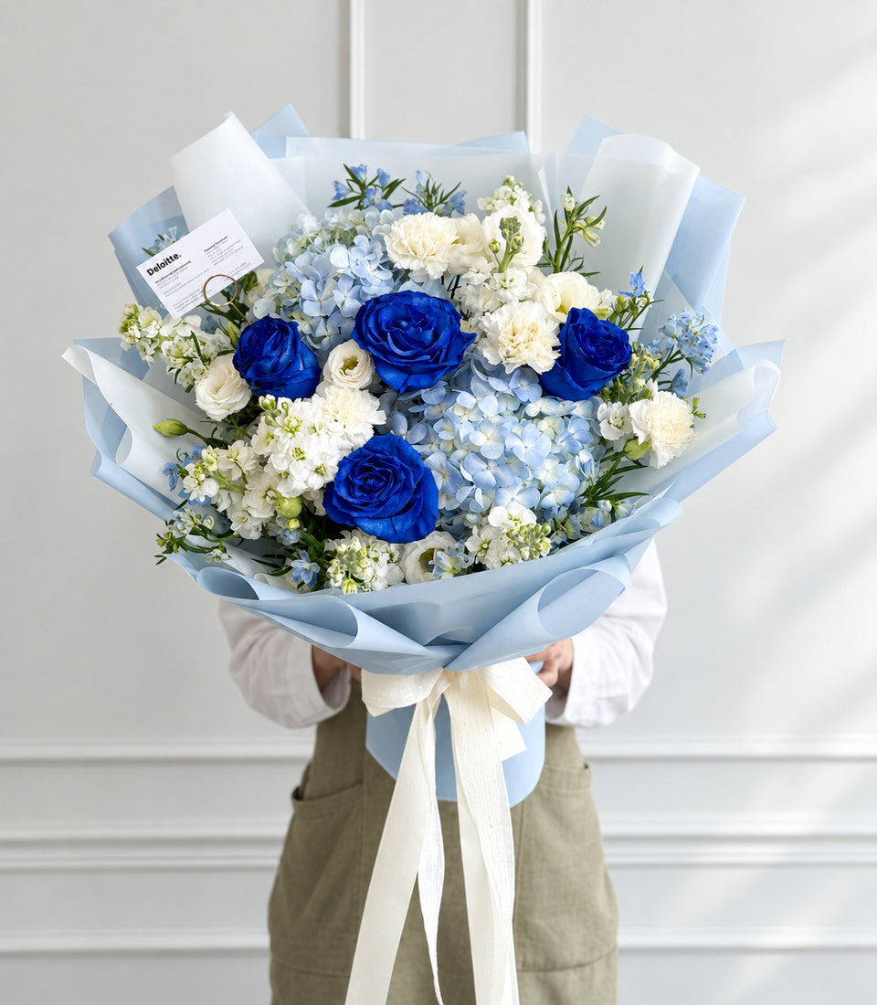 Full front model-held view of blue rose and hydrangea white flower bouquet