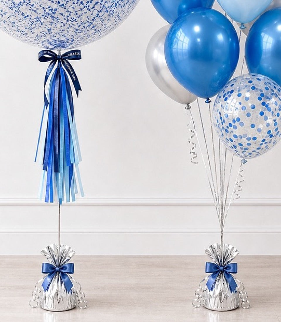 Blue and white balloon bouquet with confetti-filled and metallic balloons, ribbon tassels, and silver weights with blue bows.