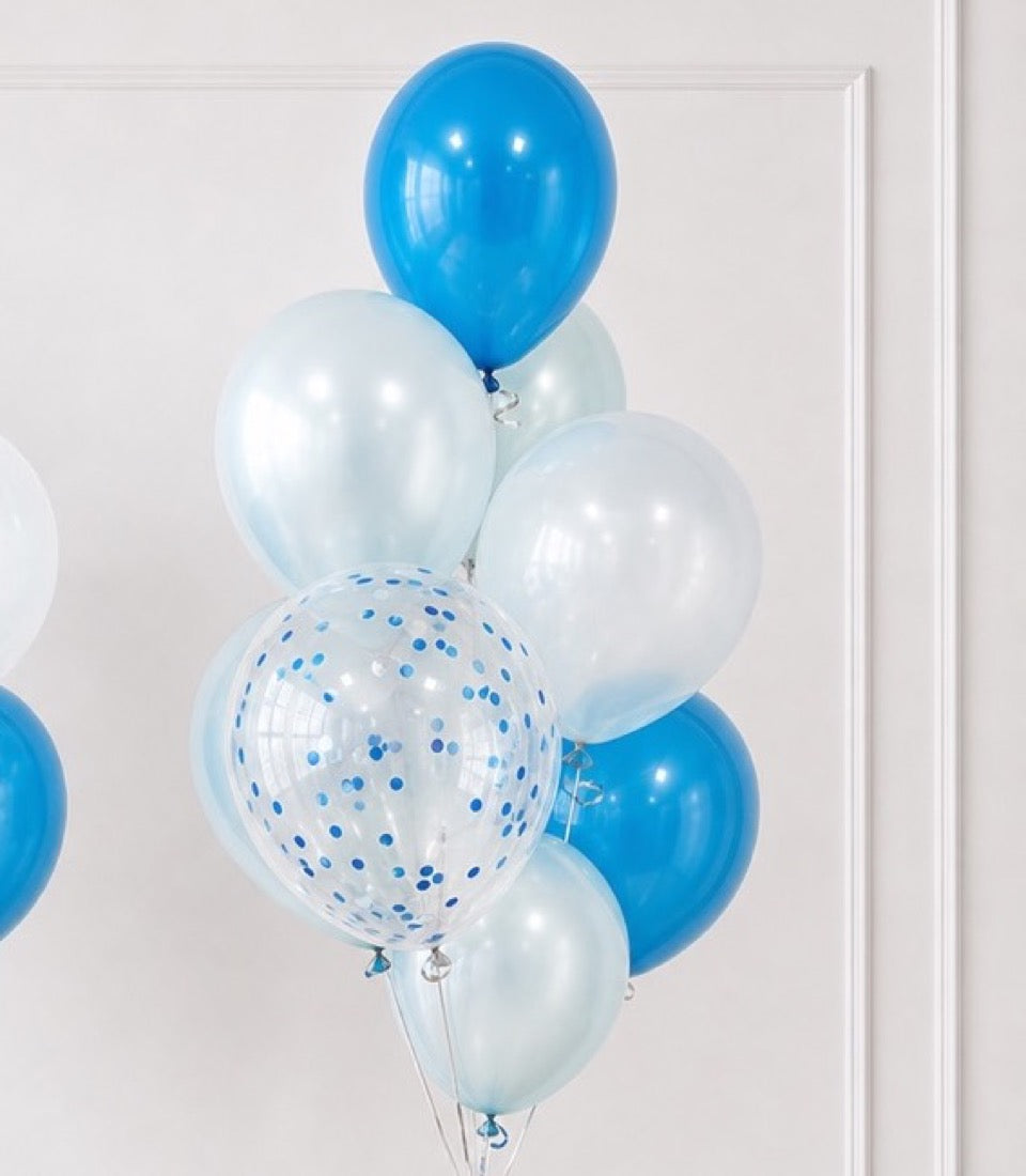 Blue and white helium balloons bouquet with pearl finish and blue confetti-filled balloon, tied with ribbons against white wall.