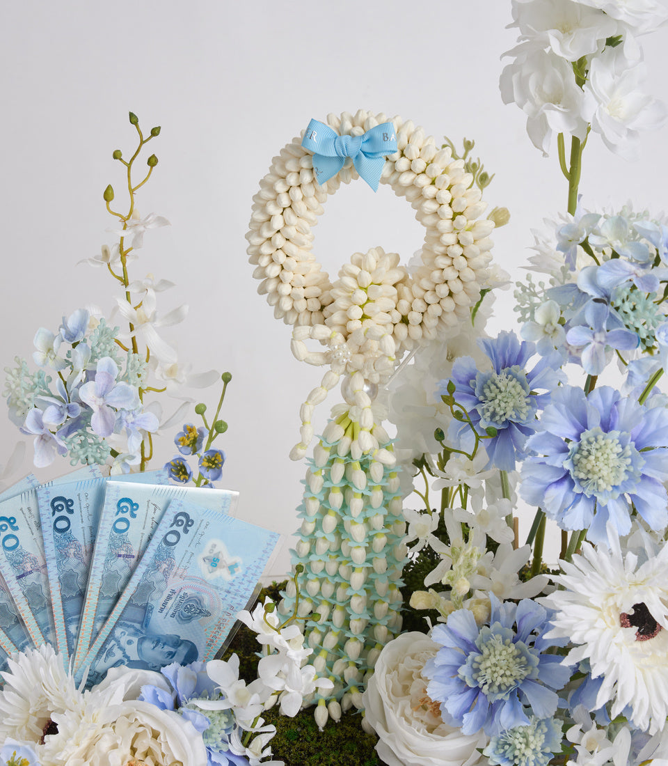 Decorative floral arrangement featuring white pearl beads forming a number 8 with blue bow, surrounded by blue and white flowers and cash notes.