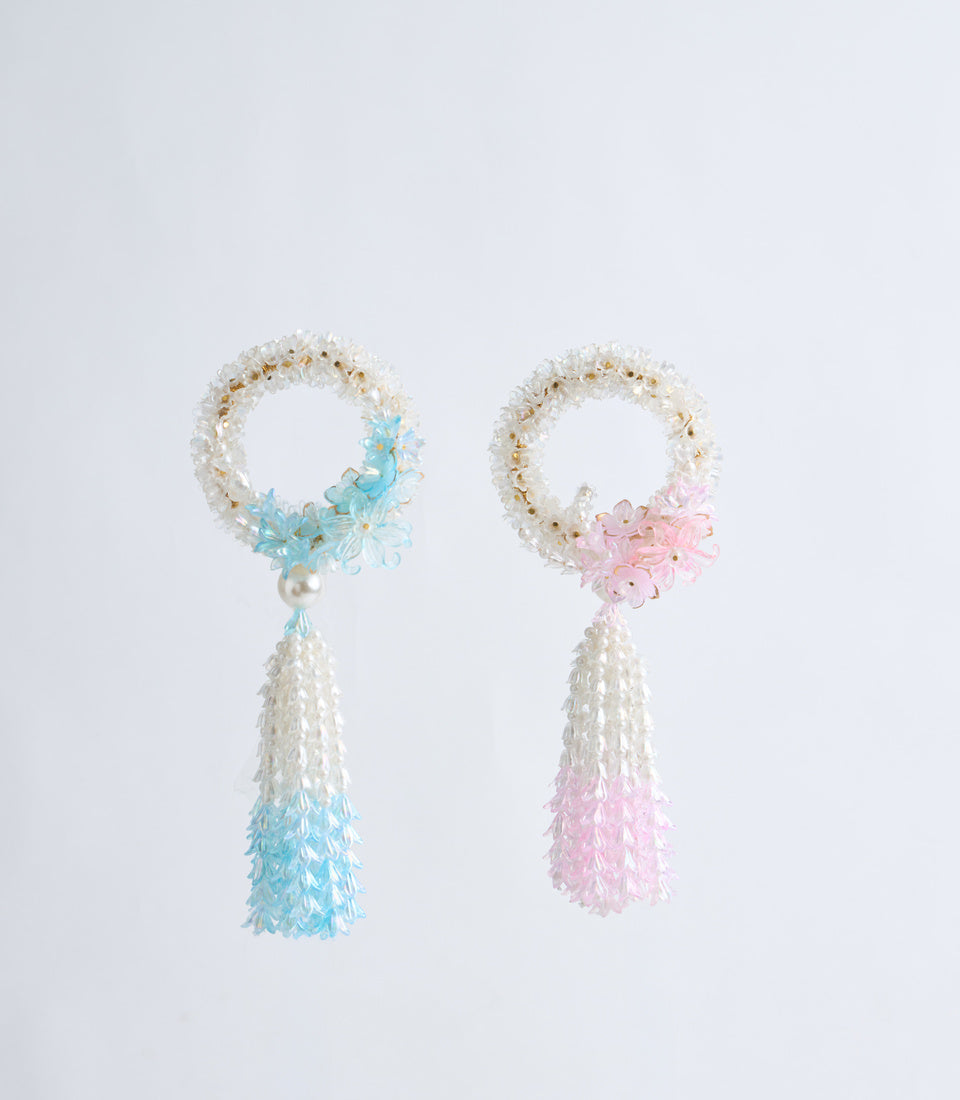Two beaded flower tassel bracelets with cream seed bead circles, one with blue flowers and tassel, one with pink flowers and tassel.