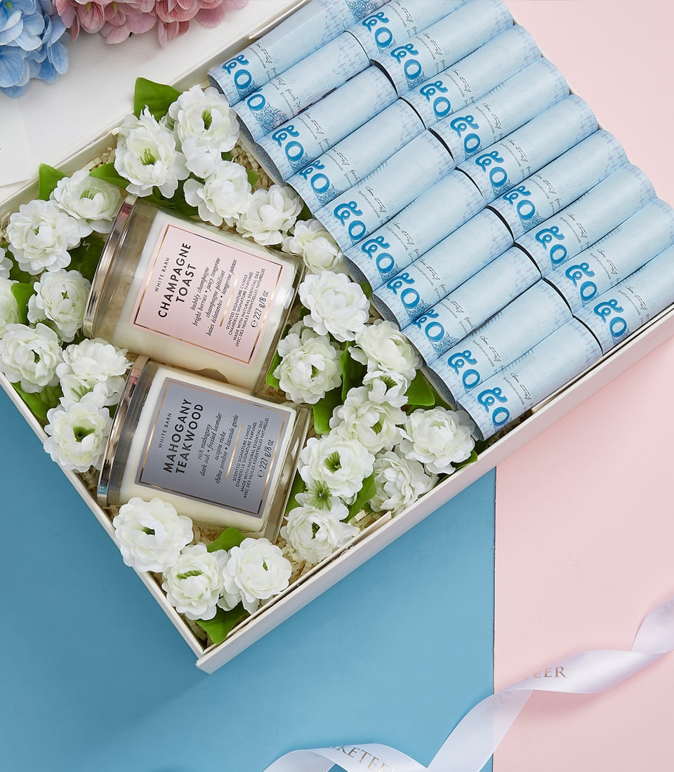 Luxury Mother's Day gift basket with champagne and teakwood candles, white flowers, and premium spa aromatics