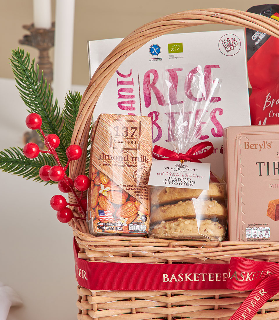 Woven wicker gift basket with tiramisu chocolate cookies, almond milk, and gourmet treats tied with red ribbon, New Year