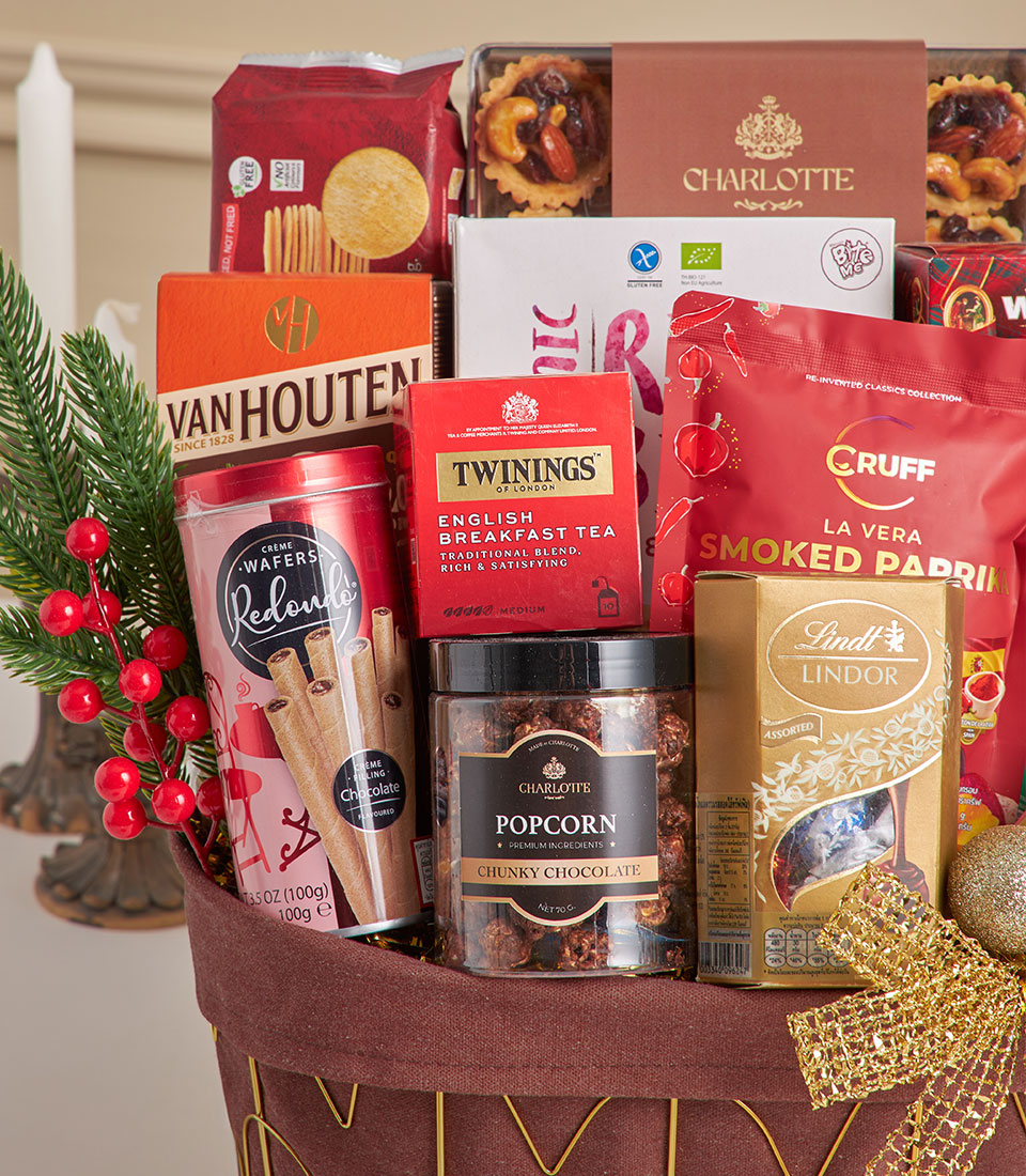 Festive New Year gift hamper with gourmet chocolates, tartlets, tea, and artisan snacks in dark fabric basket with gold