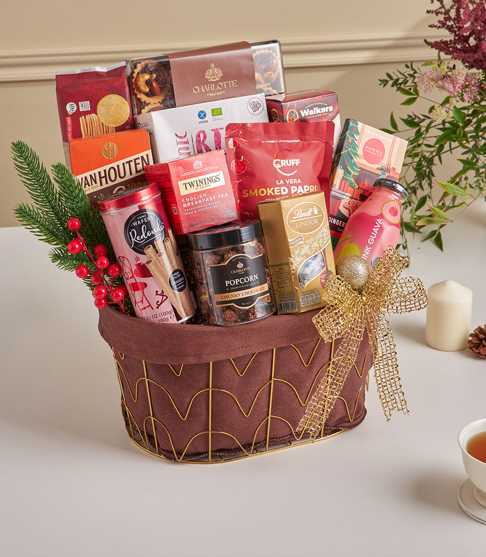 Luxe gourmet New Year gift hamper with artisan tarts, chocolates, tea, and premium snacks in gold wire basket