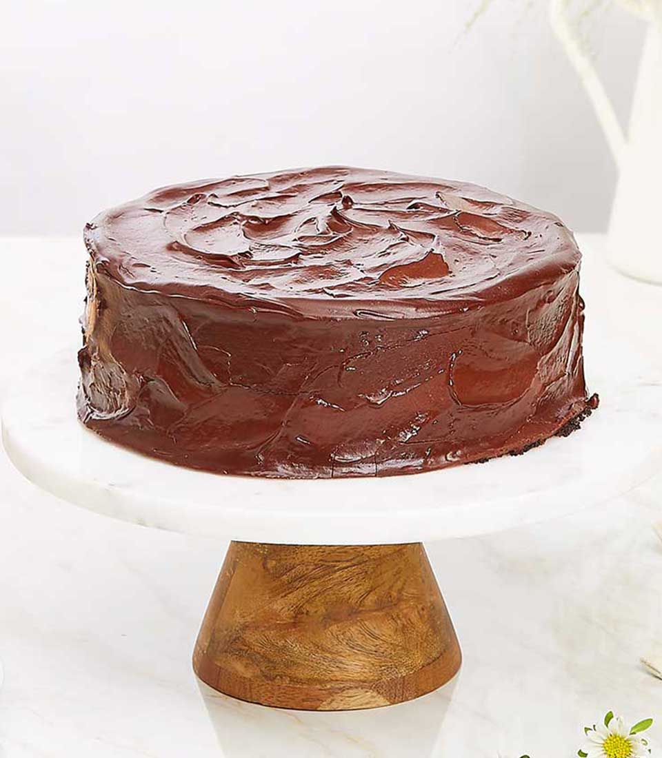 Decadent dark chocolate ganache cake on marble stand with swirled frosting top