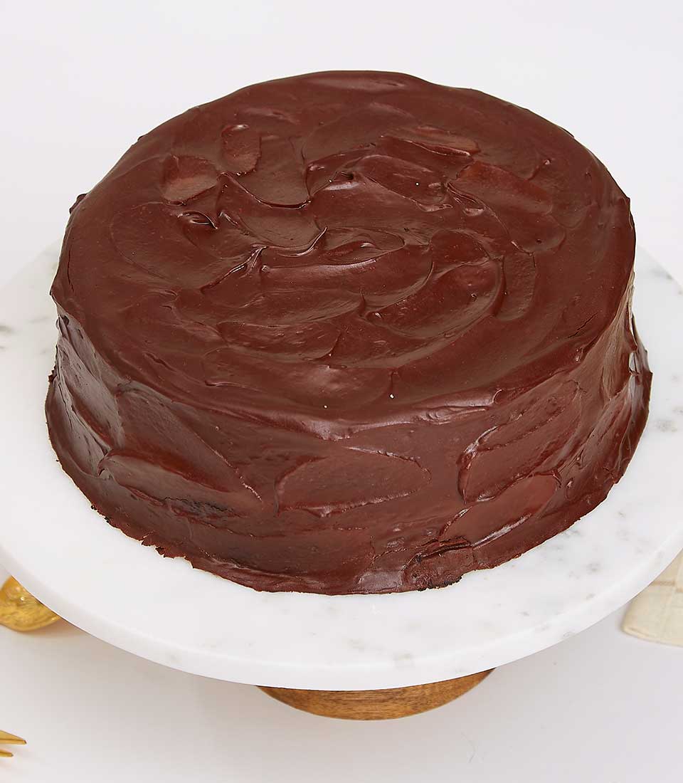 Dark chocolate cake with rich glossy frosting on marble stand, artisan celebration dessert