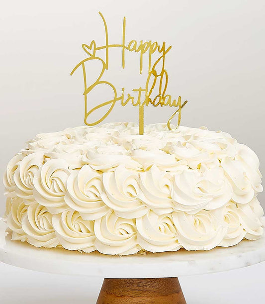 White buttercream birthday cake with gold Happy Birthday topper on marble stand