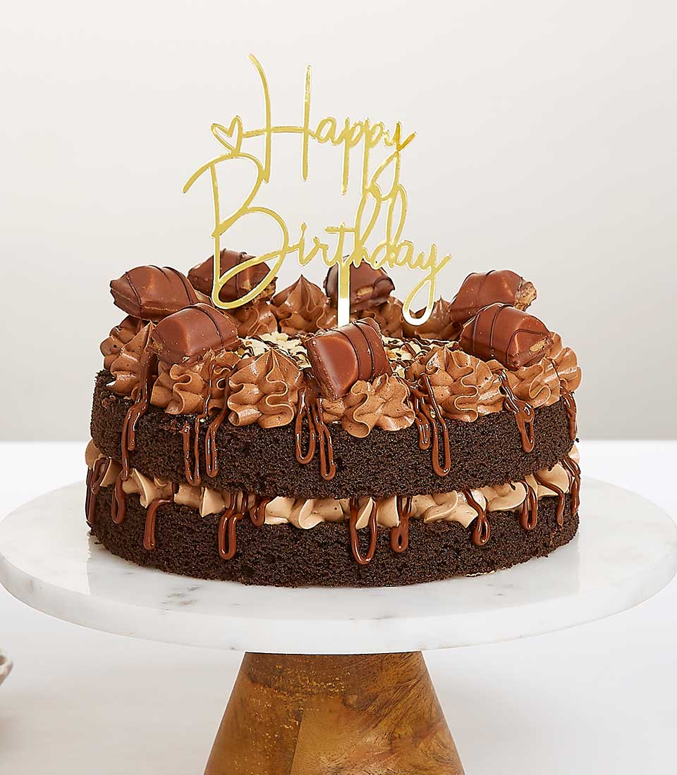 Chocolate birthday cake with Nutella and Kinder Bueno, gold Happy Birthday topper on marble stand