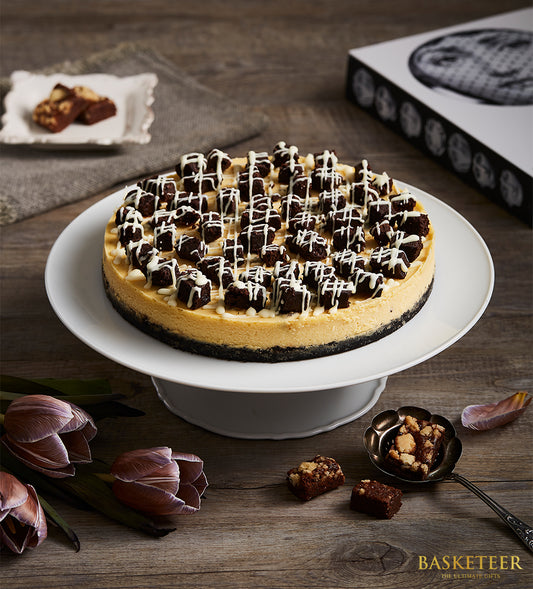 Brownie cheesecake with white icing and purple tulips, birthday gift presentation on cake stand