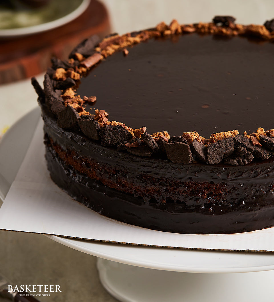 Decadent dark chocolate layer cake with glossy ganache and cookie crumb border, perfect for celebrations