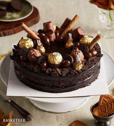 Rich dark chocolate birthday cake with ganache, cookie crumbles, chocolate shards, and topped with Ferrero Rocher, truffles,