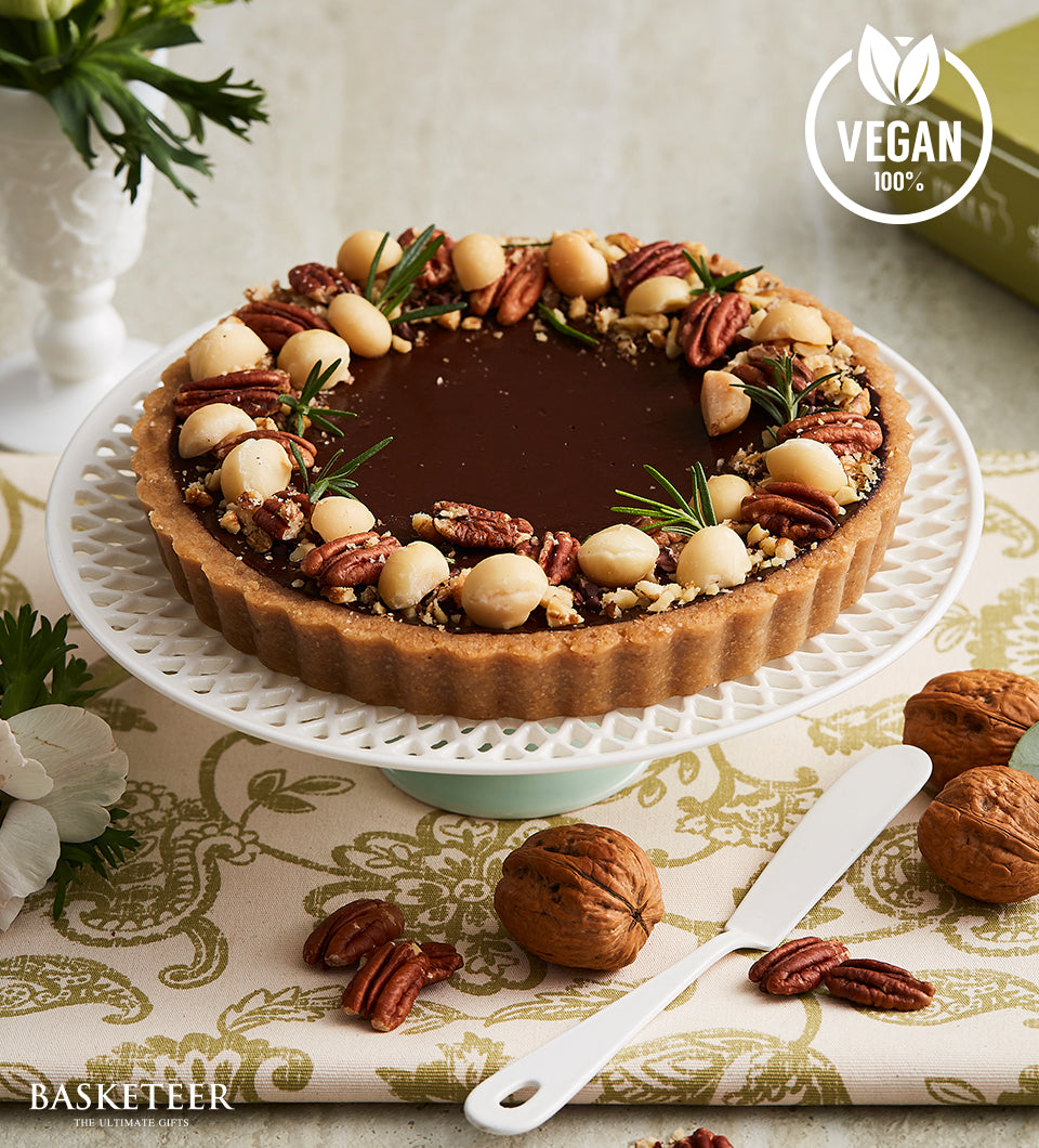 Dark chocolate vegan tart with macadamia nuts and rosemary on cake stand, birthday gift from Basketeer's artisan bakery