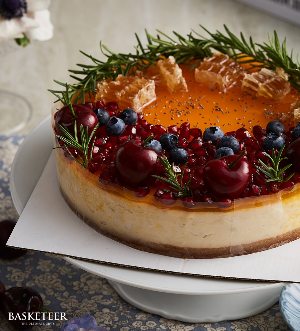 Berry Honey Cheesecake with honeycomb, blueberries, and pomegranate on white cake stand