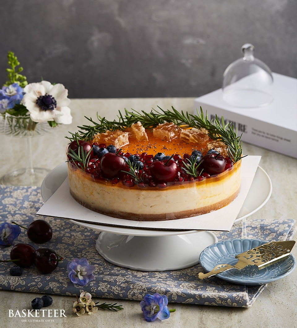 Berry honey cheesecake with fresh cherries, blueberries, and honeycomb on white cake stand